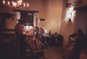 The foreman makes a pinata with two children while a woman holding a guitar watches